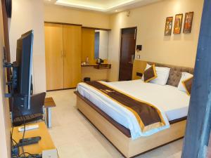 a bedroom with a bed and a flat screen tv at NAKSHATRA Hotel, Restaurant & Banquet in Barddhamān