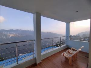 a balcony with two chairs and a view at Hotel Hill Edge in Kodaikānāl