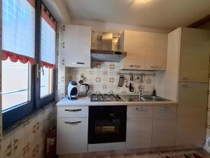 eine Küche mit weißen Schränken, einer Spüle und einem Fenster in der Unterkunft Tra le Vette in Caspoggio