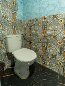 a toilet in a bathroom with mosaic tiles on the wall at TAMOUNT Surf House in Agadir
