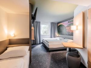 a hotel room with two beds and a desk at B&B Hotel Nürnberg-City in Nuremberg