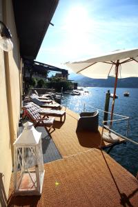 a patio with chairs and an umbrella and the water at Darsena di Riva Grande in Moltrasio