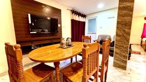 a dining room with a wooden table and a television at Hotel Hill Edge in Kodaikānāl