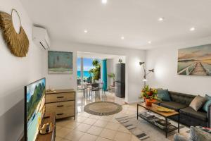 a living room with a couch and a tv at Watalibi - Beachfront apartment Grand-Case in Grand Case