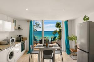 a kitchen with a table and a kitchen with a view of the ocean at Watalibi - Beachfront apartment Grand-Case in Grand Case