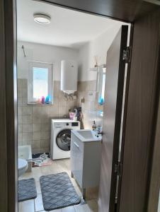 a bathroom with a sink and a washing machine at Kravica Oasis in Ljubuški