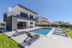 a villa with a swimming pool and lounge chairs at Villa Josip in Sukošan