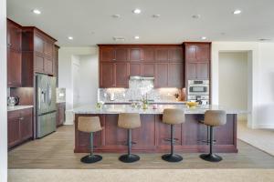 a kitchen with wooden cabinets and a large island with bar stools at Private Yard & Patio! Modern Manteca Gem in Manteca
