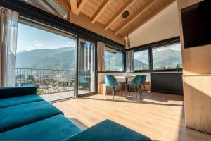 a living room with a blue couch and large windows at Echo - Private Spa Apartments in Ponte di Legno