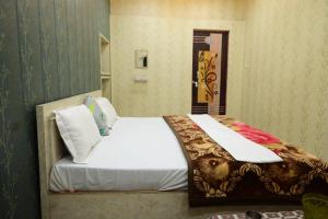a bedroom with a large bed with white sheets at Vaishno Atithi Bhawan in Naimishāranya