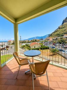 a patio with a table and chairs on a balcony at Hotel Euro Moniz in Porto Moniz