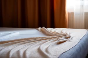 a close up of a bed with a white blanket at Pensiunea ORIENT in Brăila