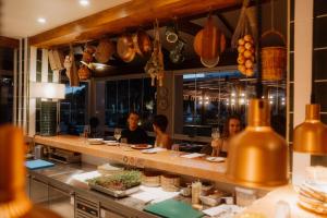 a group of people sitting at a counter in a restaurant at Kimpton Quinta da Marinha by IHG in Cascais