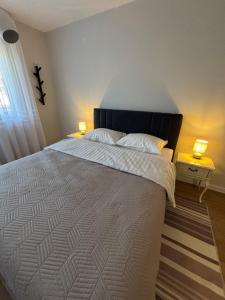a bedroom with a large white bed with two lamps at Apartman Vila&Vera in Sremska Mitrovica