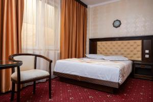 a bedroom with a bed and a chair and a table at Pensiunea ORIENT in Brăila