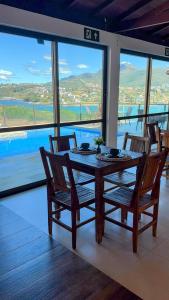 a dining room table with chairs and a view of the water at Pousada Capitólio in Capitólio