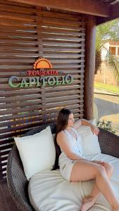 a woman is sitting on a wicker couch at Pousada Capitólio in Capitólio