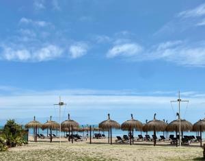 a group of straw umbrellas on a beach at Apartamento El Mar Azul 5 in Torremolinos