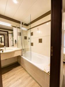 a bathroom with a shower and a tub and a sink at Hotel Euro Moniz in Porto Moniz