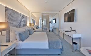 a bedroom with a large white bed and a desk at Hotel White Lisboa in Lisbon