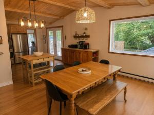 a dining room with a wooden table and a kitchen at Chalet avec spa et lac privé in Saint Come