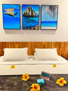 a bedroom with a bed with four pictures on the wall at Pousada do Vale in Fernando de Noronha