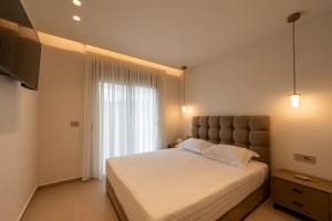 a bedroom with a large bed with a large window at ΛΑΚΩΝΙΖΕΙΝ Luxury Suites in Sparta