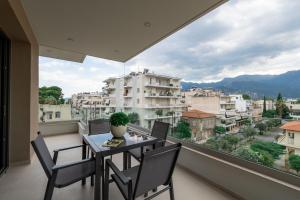 a balcony with a table and chairs and a large window at ΛΑΚΩΝΙΖΕΙΝ Luxury Suites in Sparta