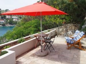 a table and chairs under a red umbrella on a patio at Perla Vacation Home in Sutivan