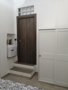 a brown door in a white room with stairs at Prima Stella Tourist Rooms in Minturno
