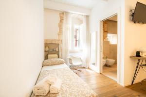 a bedroom with two beds and a television and a bathroom at Iulius Suite in Conversano