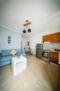 a living room with a blue couch and a kitchen at Casa Damour in Sidari