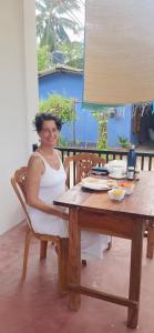 a woman sitting in a chair at a wooden table at Sivas friendly guest house in Nilaveli