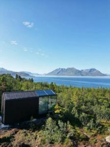a glass house on the shore of a lake at WonderInn Arctic in Utstrand