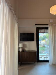 a living room with a television and a window with curtains at athanasian side sea view home in Polychrono