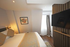 a bedroom with a bed and a flat screen tv at Mercure London Paddington Hotel in London