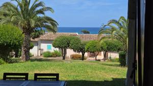 a view of a house with palm trees and the ocean at Favone Mini Villa Playa del Oro in Favone