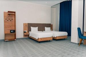 a bedroom with two beds and a blue curtain at Hanzade Palace in Samarkand