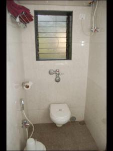 a small bathroom with a toilet and a window at On Point Plaza in Murud
