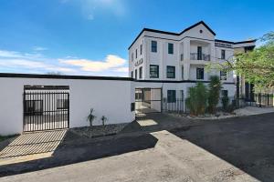 a white building with a gate in a parking lot at Airport Lodge Hotel in Kempton Park