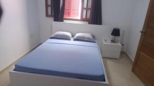 a bed in a white room with a blue mattress at Sossego & Conforto in Espargos