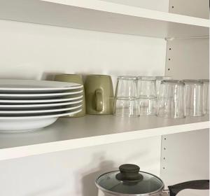 a kitchen shelf with plates and dishes on it at Lk Apartments in Halmstad