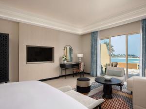a hotel room with a bed and a television and a living room at Sofitel Ras Al Khaimah Al Hamra Beach Resort in Ras al Khaimah +115 photos