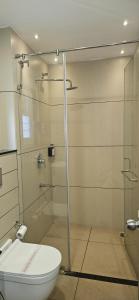a bathroom with a toilet and a glass shower at The Executive Inn in Siliguri +27 photos