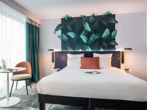 a bedroom with a large bed with a large painting on the wall at ibis Styles Bezons Paris La Défense in Bezons