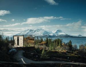 a house on the shore of a lake with snow covered mountains at WonderInn Arctic in Utstrand