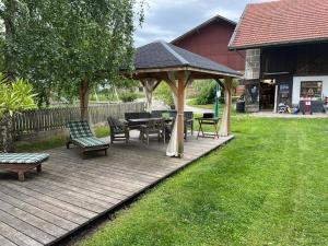 a wooden deck with a gazebo with a table and benches at Auf der Woad in Tittmoning