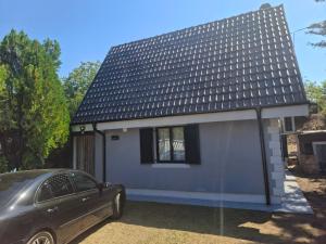 a small white house with a car parked in front at Vikendica DUNAV in Golubac