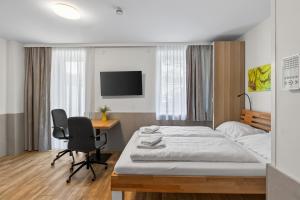 a bedroom with a bed and a desk and a tv at AJO Apartments - Vetmed - Self-Check-in in Vienna