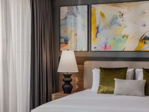 a bedroom with a bed with a lamp and a painting at Mercure Brisbane Spring Hill in Brisbane